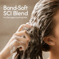 Woman applying a bond-care shampoo bar to wet hair and working it into a creamy lather