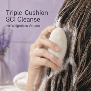 Woman applying a solid volumizing shampoo bar to wet hair and working it into a creamy lather